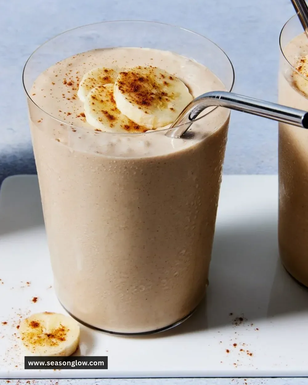 A creamy Peanut Butter Banana Smoothie in a glass with bananas and peanut butter.
