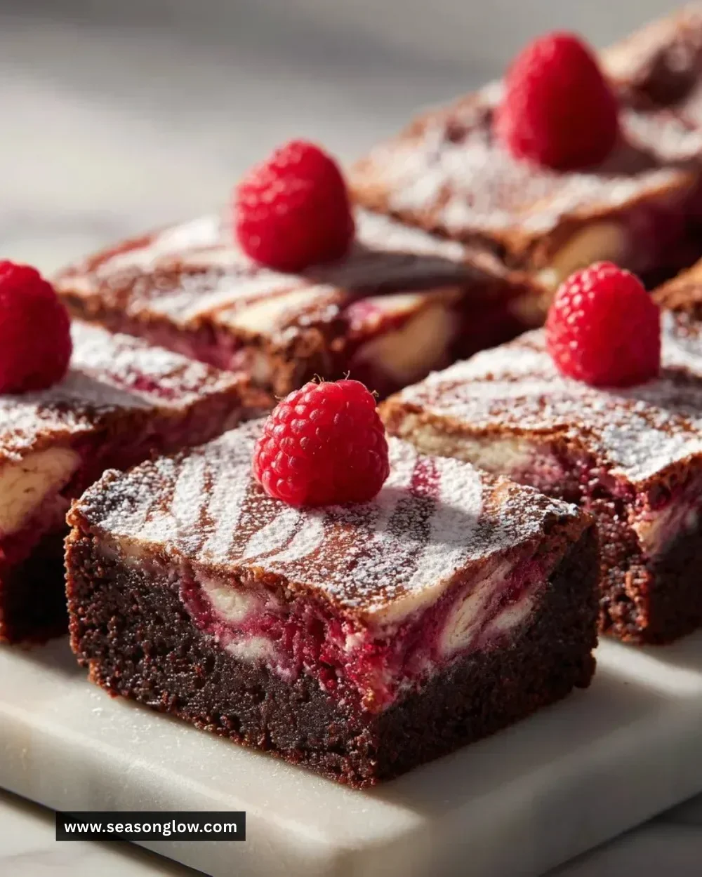 Delicious raspberry brownies topped with fresh raspberries and chocolate drizzle.