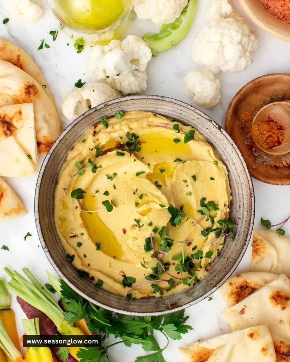 Bowl of creamy red lentil hummus with veggies and pita bread