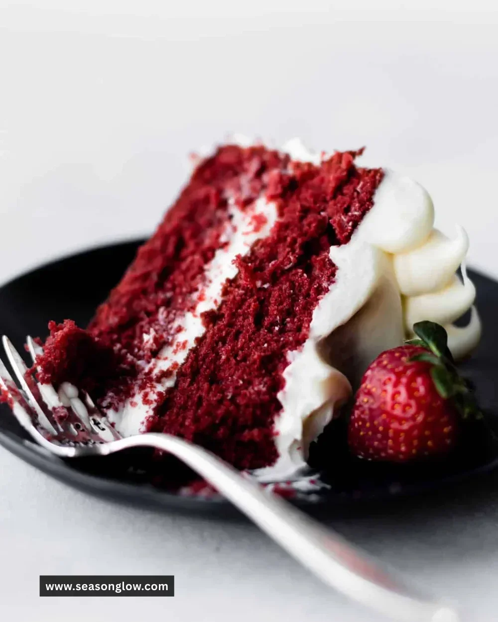 Delicious red velvet cake with creamy cream cheese frosting on a white plate