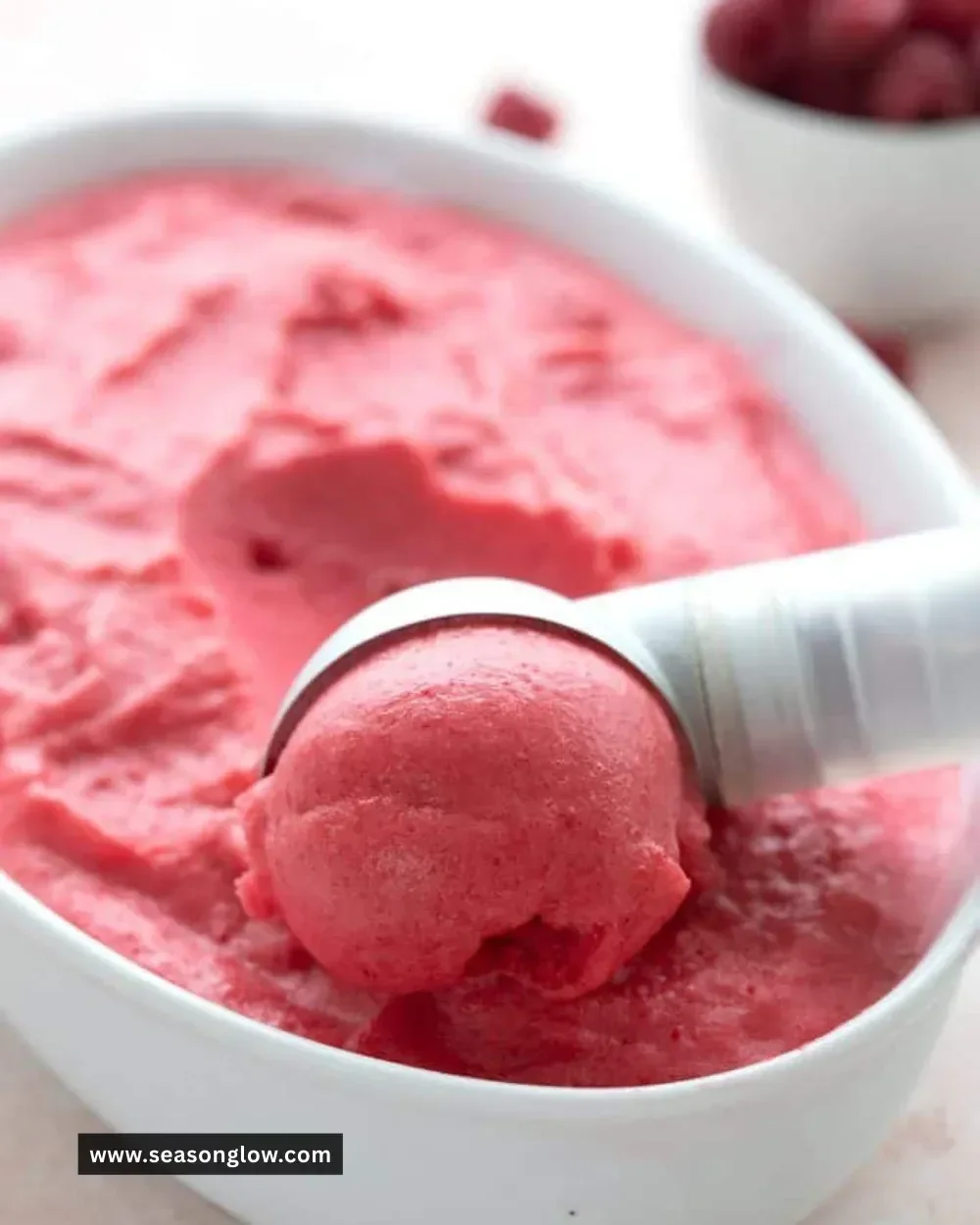 Sugar free keto raspberry sorbet in a bowl with fresh raspberries.
