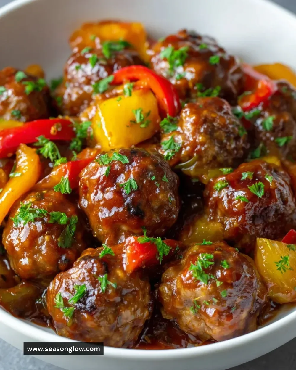 Delicious sweet and sour meatballs served with sauce and garnished.