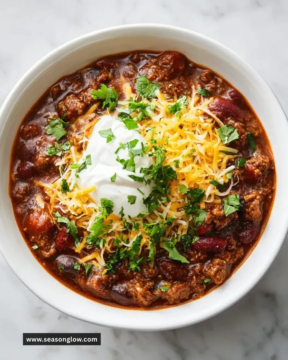 Bowl of ultimate beef chili topped with cheese and herbs