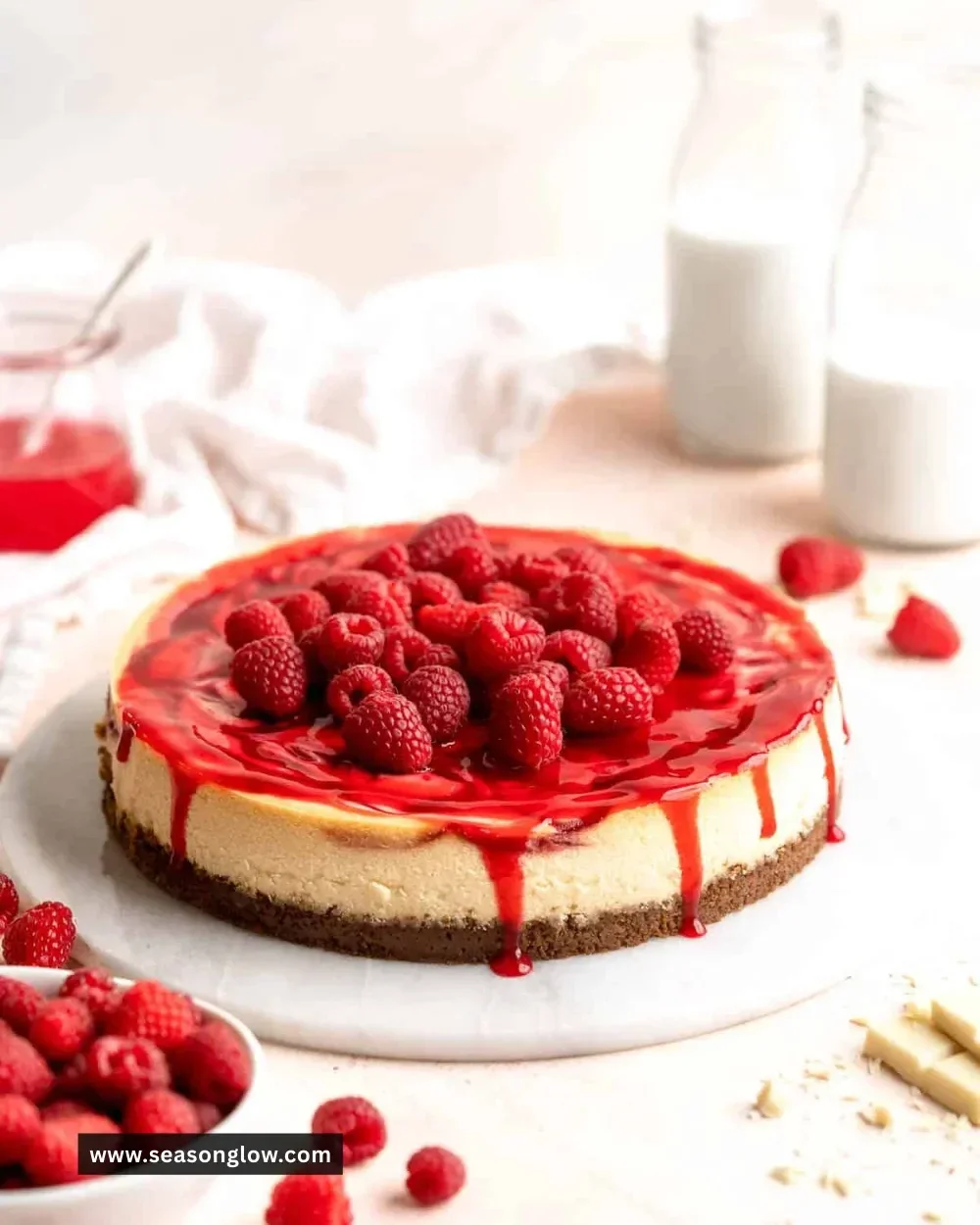 Delicious slice of White Chocolate Raspberry Cheesecake topped with fresh raspberries