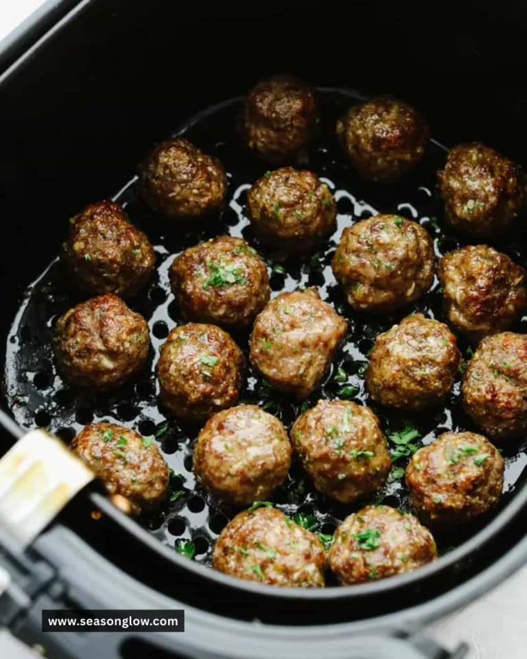 Juicy air fryer meatballs served on a plate with marinara sauce and herbs.