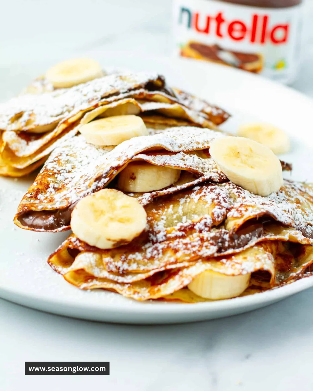 Delicious Banana Nutella crepes topped with fresh bananas and drizzled with Nutella.
