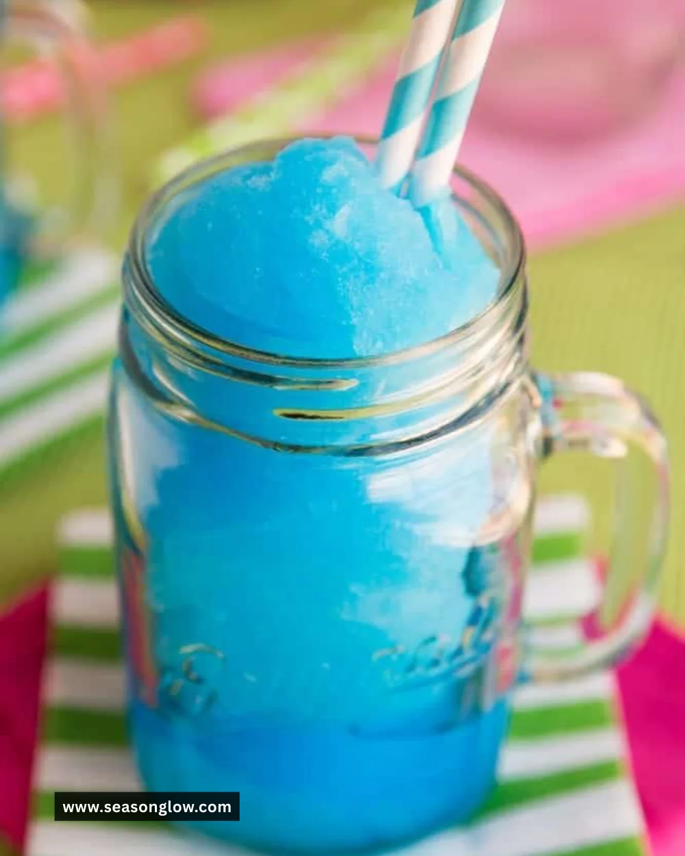Delicious blue raspberry slushie in a glass with ice and a straw