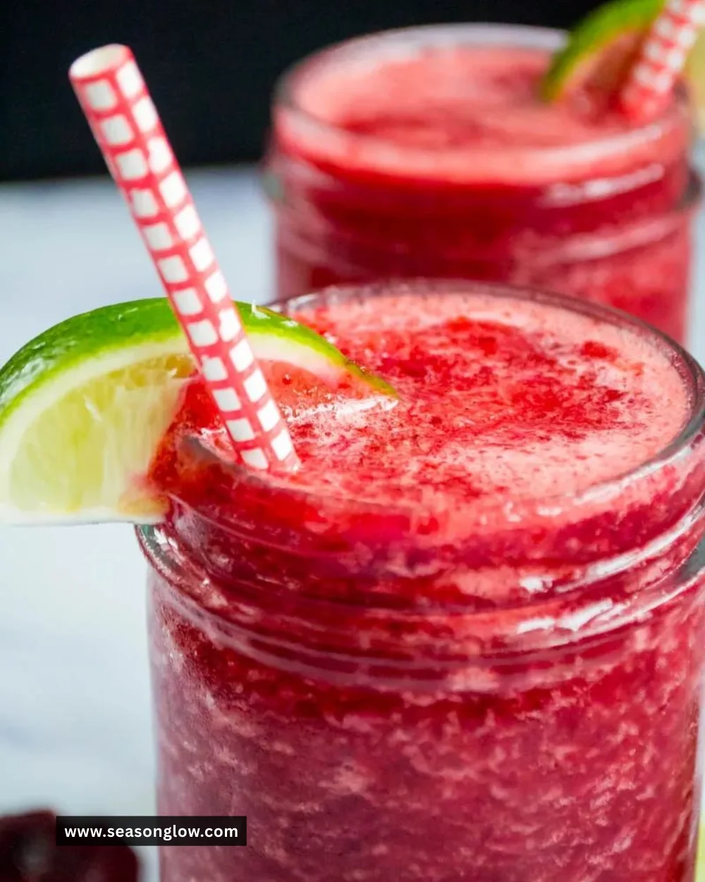 Refreshing Cherry Limeade Slushie in a glass with ice and garnished with lime