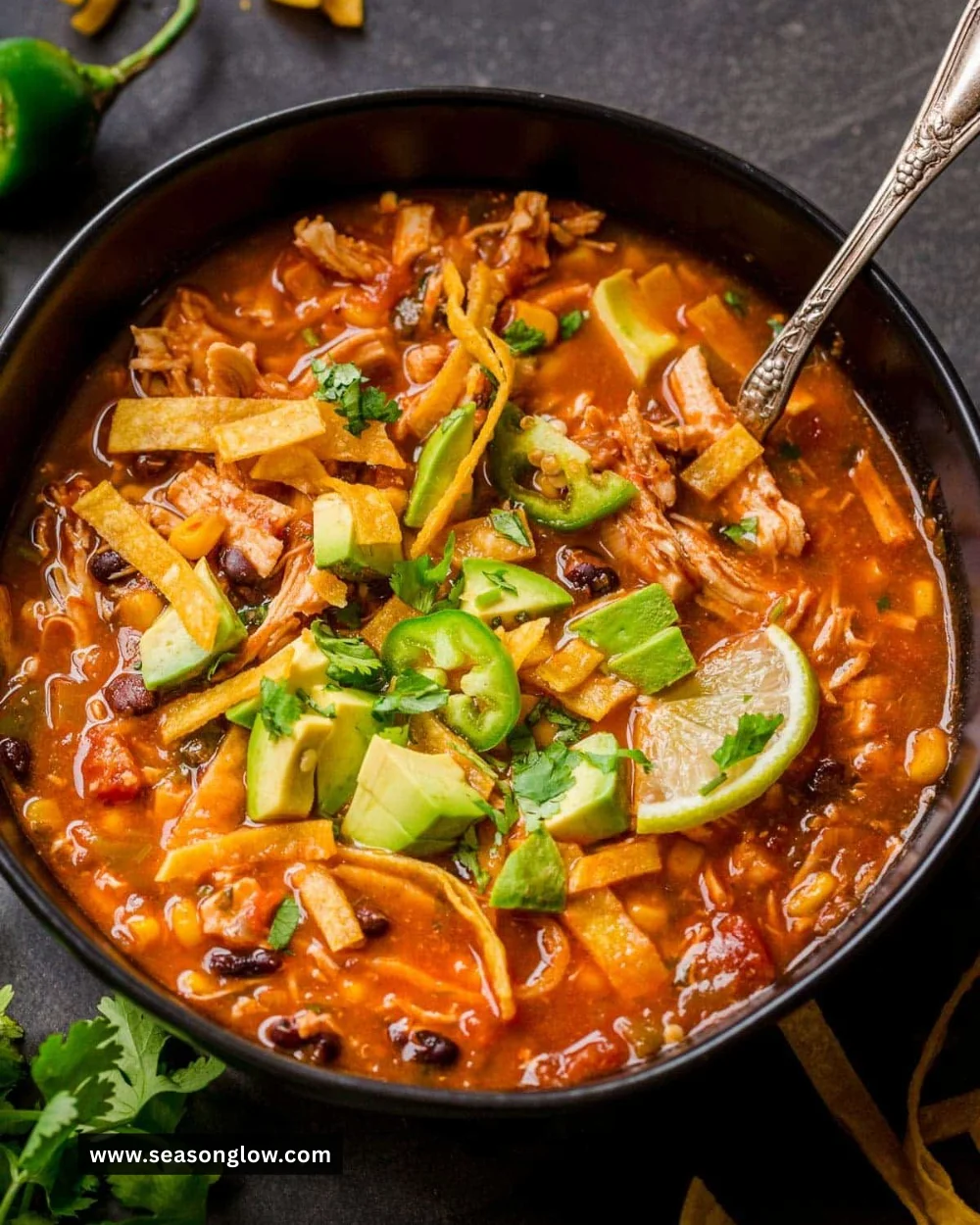 Bowl of hearty Chicken Tortilla Soup garnished with tortilla strips and fresh herbs.