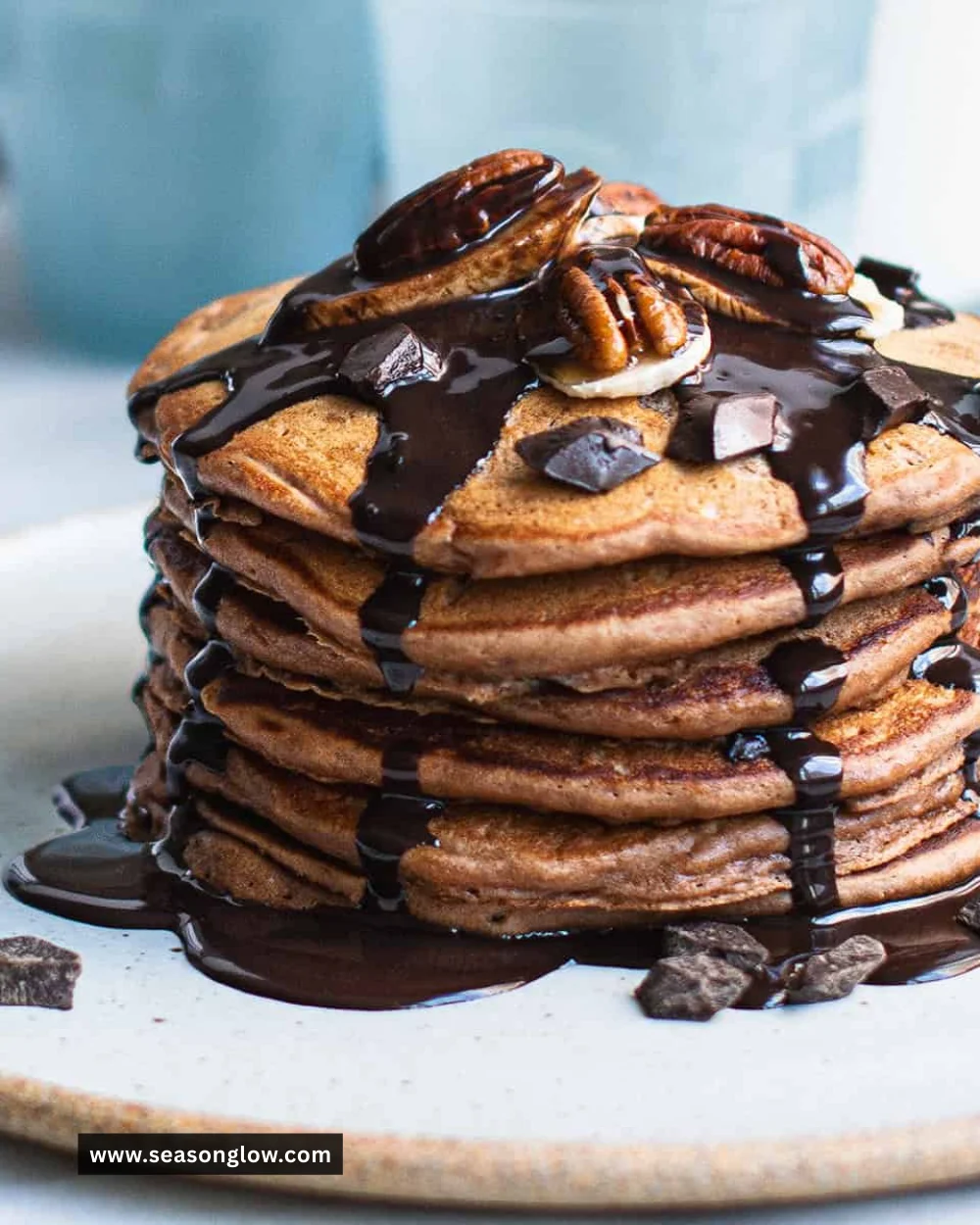 Delicious chocolate protein pancakes stacked on a plate with syrup and berries