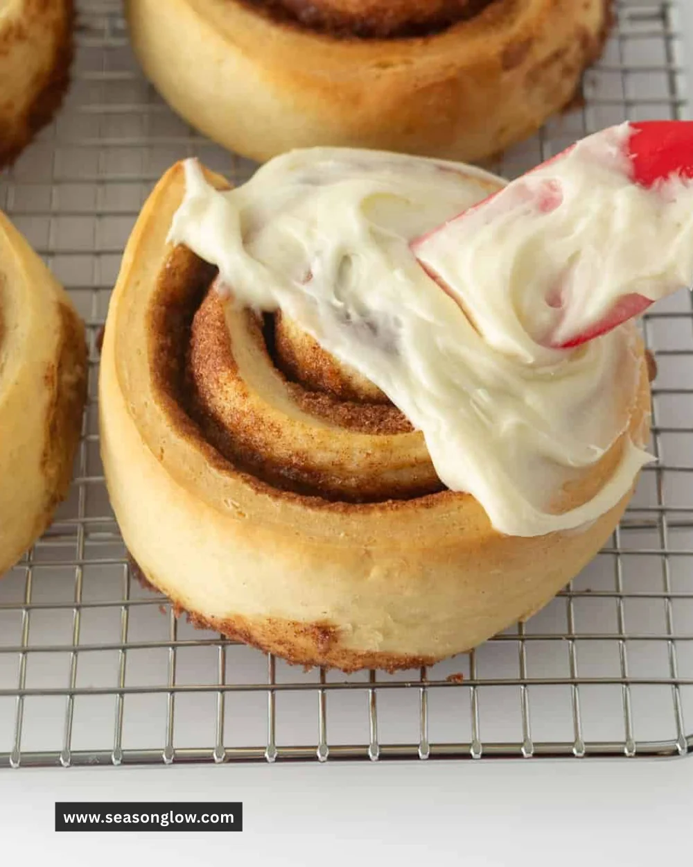 Delicious cream cheese frosting on warm cinnamon rolls