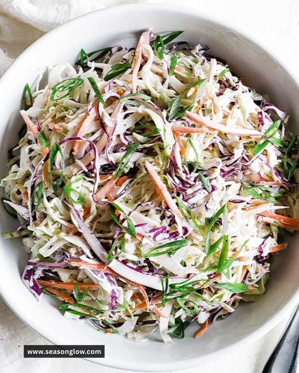 Bowl of fresh coleslaw made with cabbage and carrots, served as a side dish