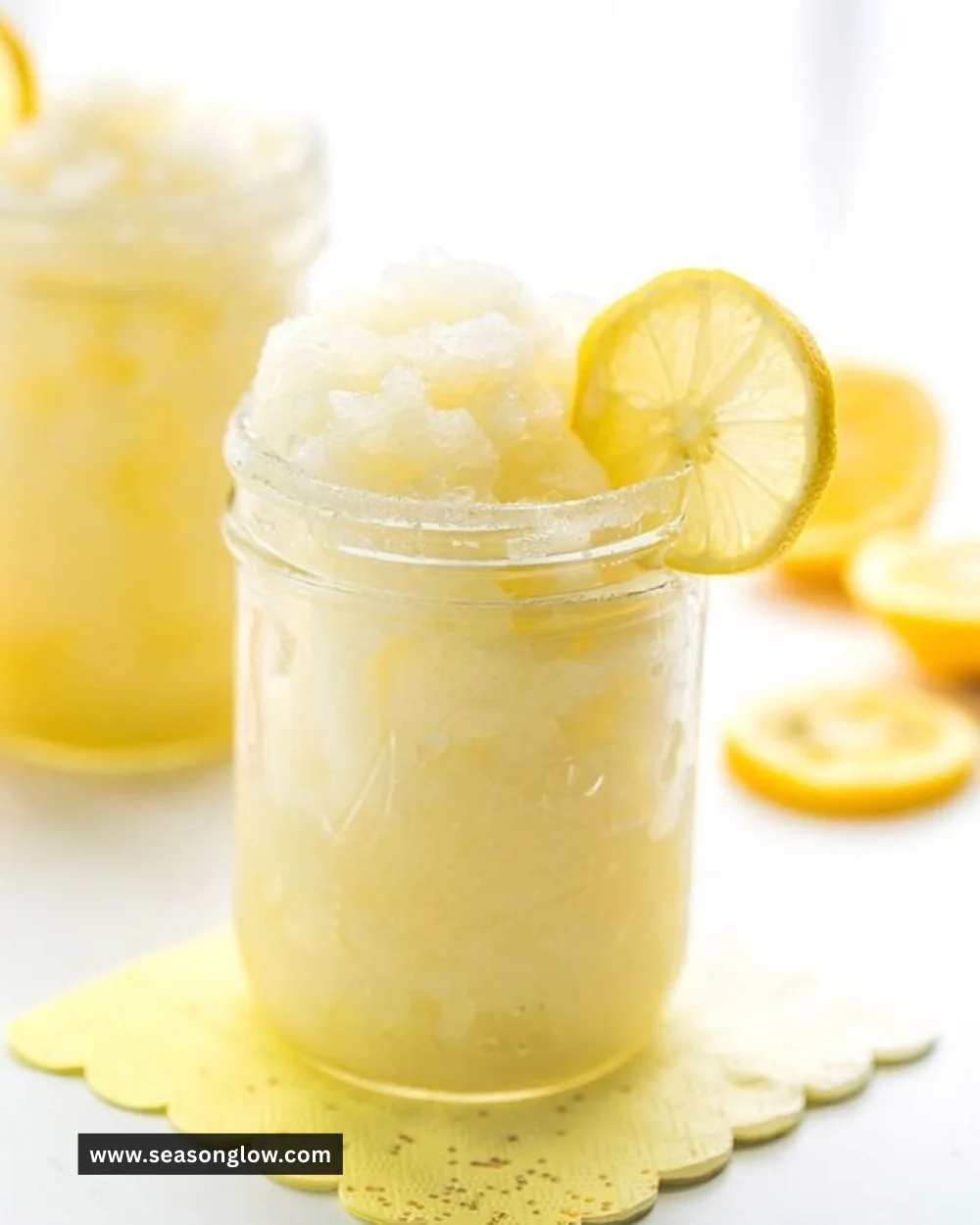 Refreshing frozen lemonade slushie in a clear glass with ice and lemon slices