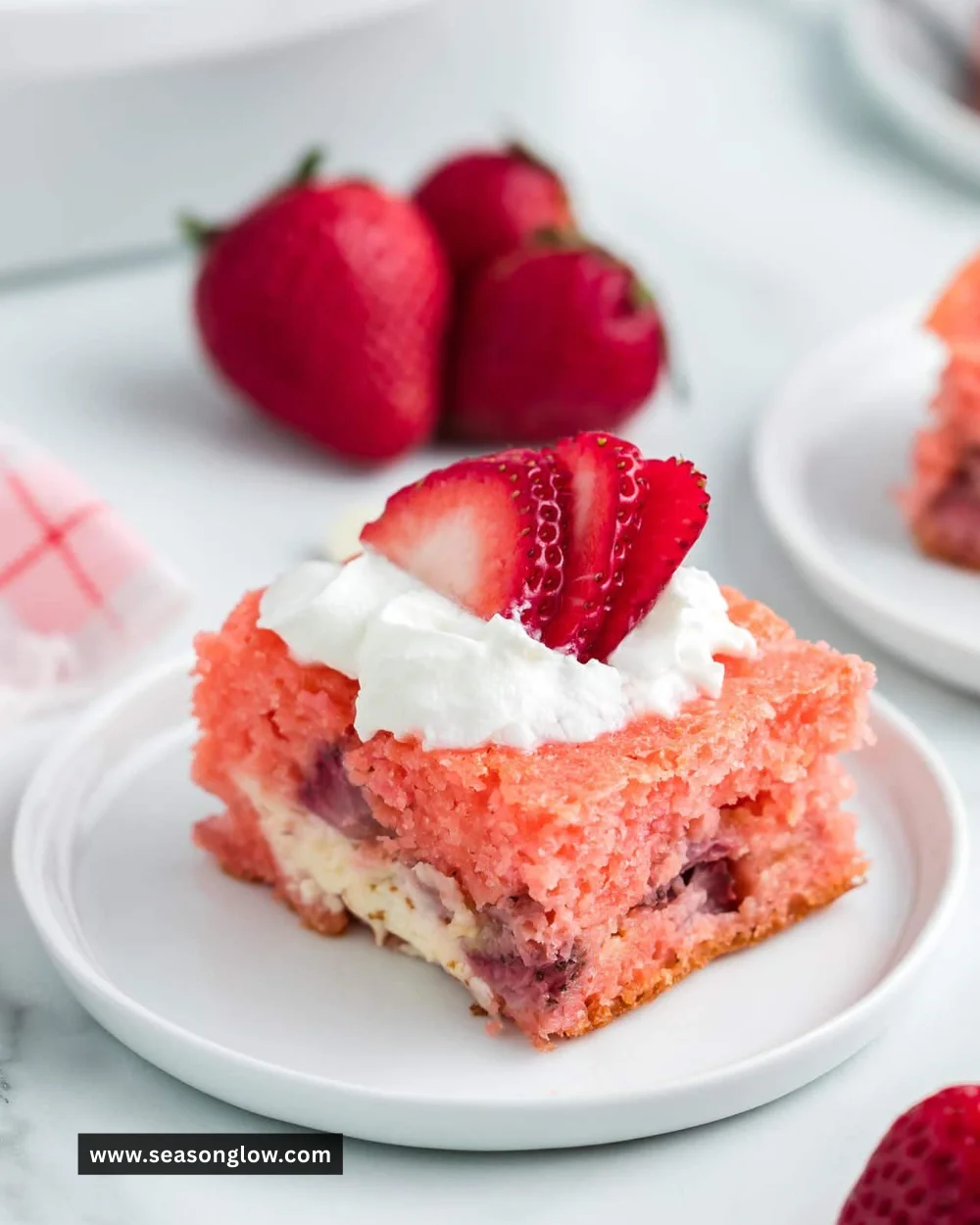 Slice of Strawberry Earthquake Cake with fresh strawberries and cream cheese frosting