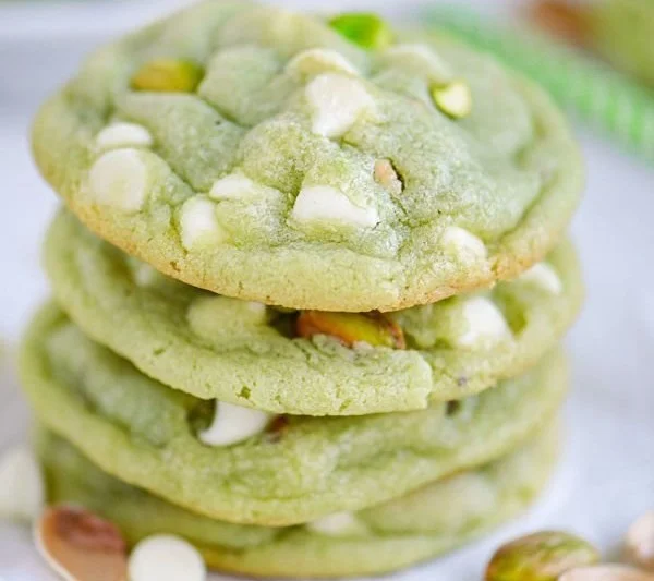 Chewy pistachio pudding cookies on a plate with green sprinkles.