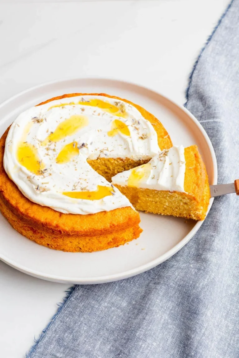 A slice of lavender honey cake garnished with edible flowers and honey drizzle.