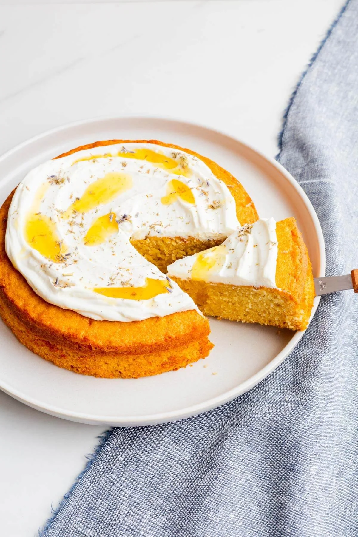 A slice of lavender honey cake garnished with edible flowers and honey drizzle.