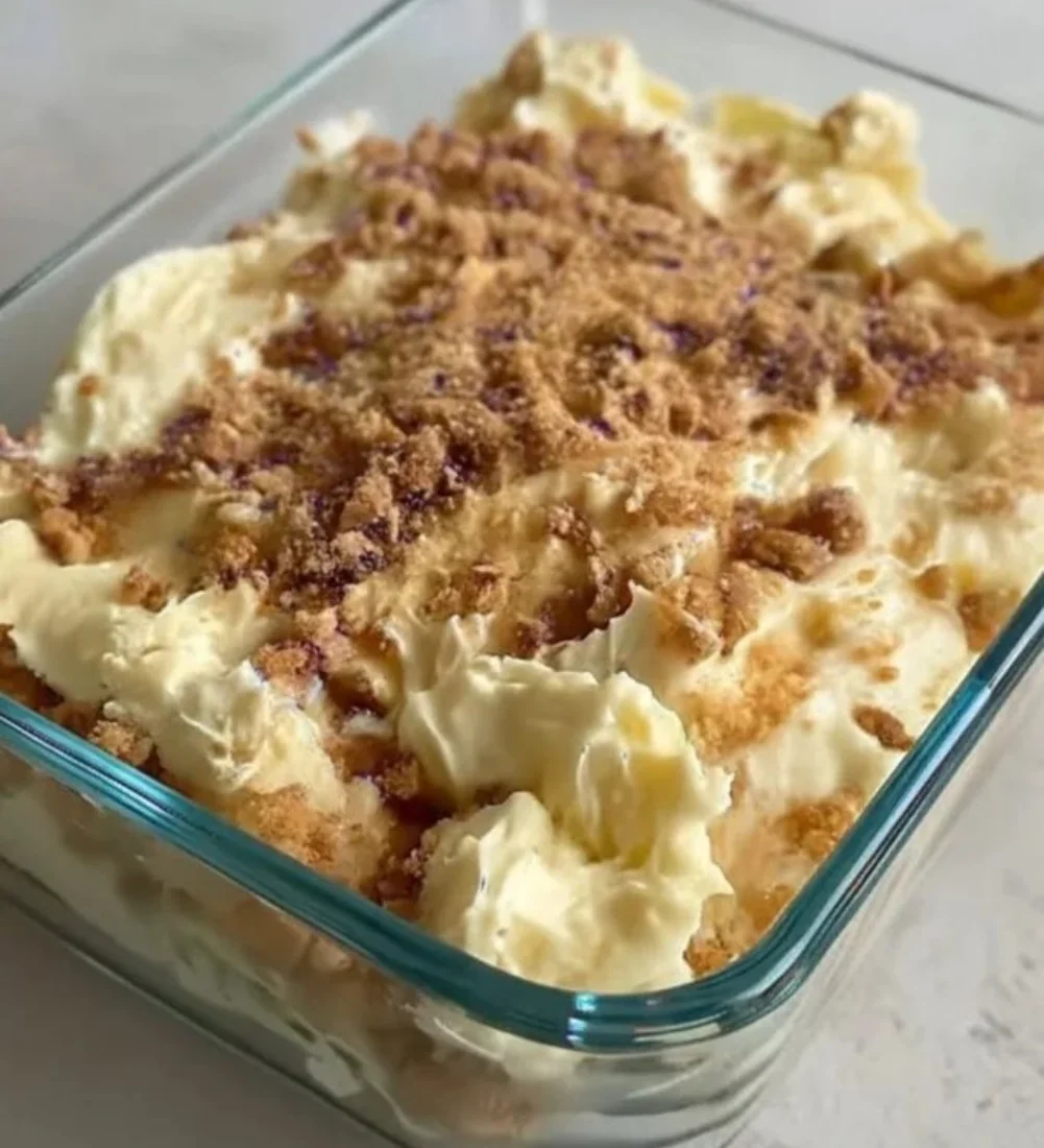 Protein banana pudding yogurt parfait in a clear glass with banana slices and granola.