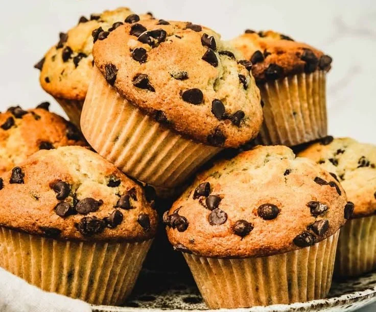 Bakery-style chocolate chip muffins with melted chocolate chips on top.