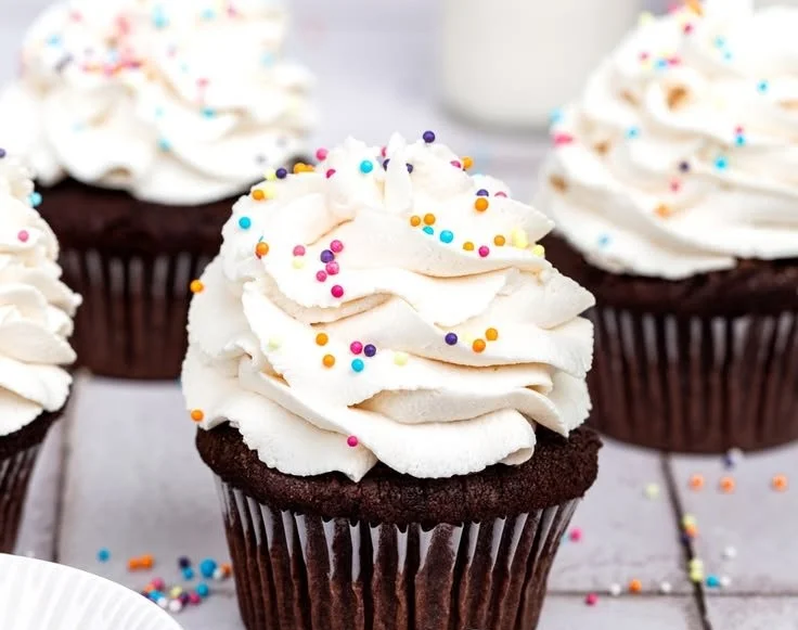 Delicious chocolate cupcakes with creamy frosting on a decorative plate.