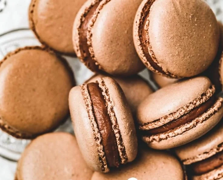 Delicious chocolate macarons displayed on a decorative plate.