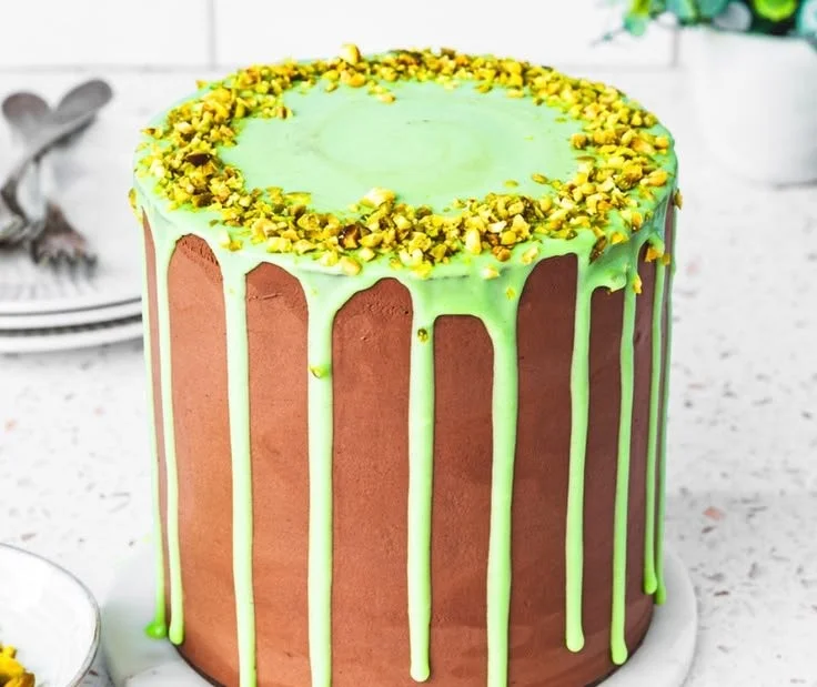 Slice of Dubai Chocolate Pistachio Cake with rich chocolate frosting and chopped pistachios.