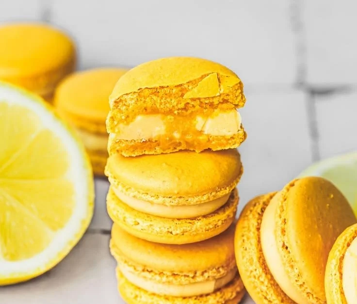 Delicious lemon macarons with a bright yellow filling on a decorative plate.