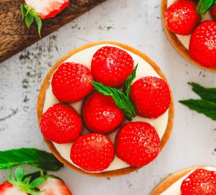 Mini strawberry tart topped with fresh strawberries and whipped cream