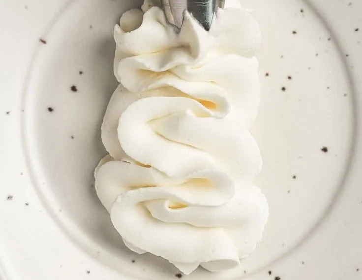 Bowl of stabilized whipped cream cheese frosting with a spatula