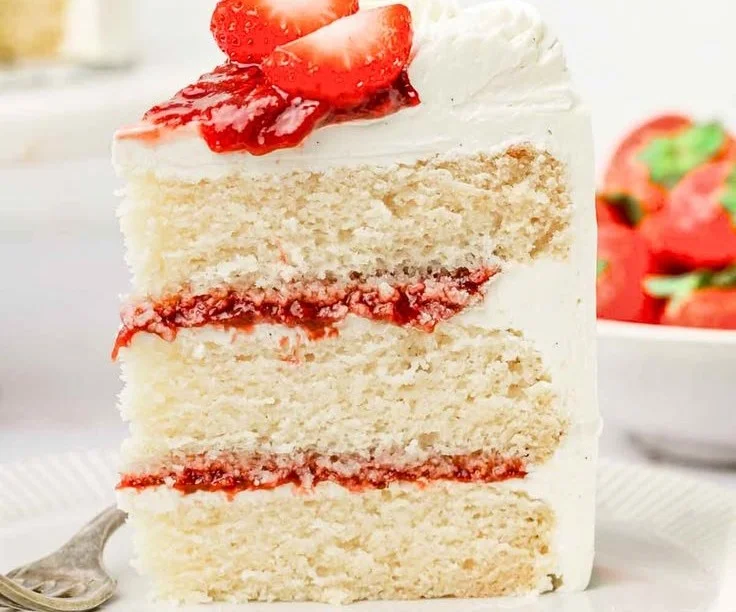 A scrumptious strawberry vanilla cake topped with fresh strawberries and creamy frosting.